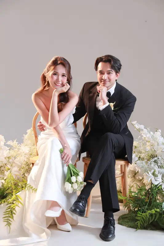 Kia Yuong and Shantanu laughing, seated among white flowers